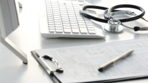Medical billing claim form, stethoscope, and keyboard on a desk representing 2027 Medicare fee schedule changes for podiatry